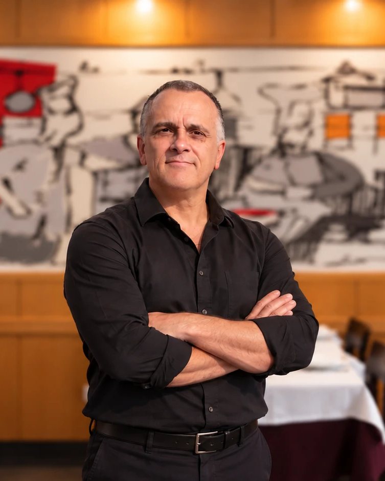 O dono do Solar dos Duques na sala, em frente ao mural da cozinha